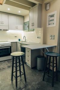 a kitchen with white cabinets and two bar stools at Katerina's Suite in Plomari