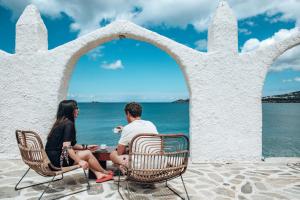 un homme et une femme assis sur des chaises en face de l'océan dans l'établissement Selina Paros, à Pounda