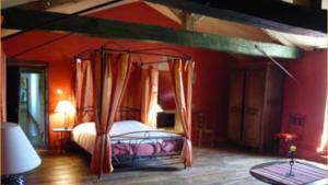 a bedroom with a canopy bed with red walls at Logis de l'Aublonnière in Sainte-Cécile