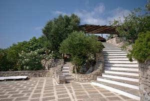 un conjunto de escaleras con árboles y una pared de piedra en TRULLO MEDITERRANEO - SANTA MARIA DI LEUCA, en Gagliano del Capo