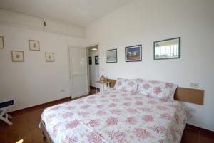 a bedroom with a bed with a floral bedspread at TRULLO MEDITERRANEO - SANTA MARIA DI LEUCA in Gagliano del Capo
