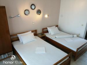 two beds in a small room with white sheets at Avra Ηouse in Kriopigi