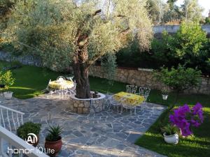 a patio with a tree and tables and chairs at Avra Ηouse in Kriopigi