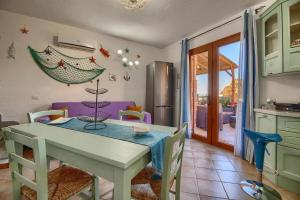 a kitchen and dining room with a table and chairs at L'Estasi Tanca Piras a bordo piscina con vista mare in Nebida