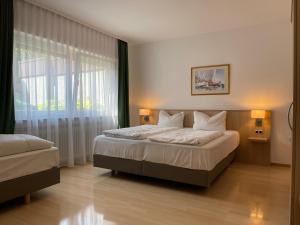 una camera da letto con due letti e una grande finestra di Hafner Hotel Apartment Self Check-In Anytime a Stoccarda
