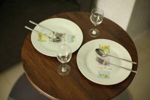two white plates and glasses on a wooden table at A2J Luxury 1BR Tagaytay Suite Near Skyranch, Malls in Tagaytay