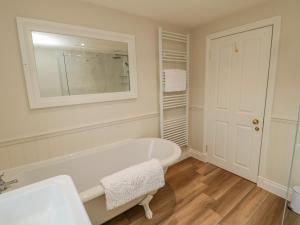 a white bathroom with a tub and a mirror at 46 Castle Street in Berwick-Upon-Tweed +37 photos