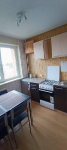 a kitchen with a stove and a table and a window at Adelės Apartamentai Panevėžyje in Panevėžys