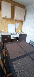 a kitchen with a table and a stove and cabinets at Adelės Apartamentai Panevėžyje in Panevėžys