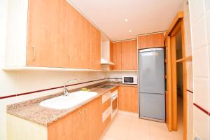 a kitchen with wooden cabinets and a stainless steel refrigerator at Expoholidays-Brisas Almerimar in Almerimar