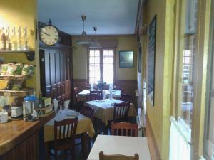 a restaurant with two tables and a clock on the wall at Hostal Les Bedules in Oseja de Sajambre