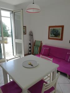 een woonkamer met een witte tafel en een paarse bank bij Casa vacanza Marina di Andrano zona Grotta Verde in Andrano