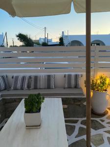 a white bench with two potted plants and an umbrella at Archipelagos Studios in Naousa