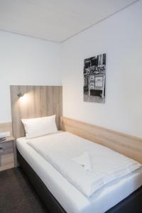 Un dormitorio con una cama blanca con una foto en la pared en Friesen Hotel, en Jever