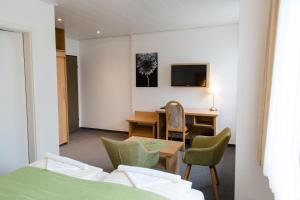 ein Hotelzimmer mit einem Schreibtisch, einem Tisch und Stühlen in der Unterkunft Friesen Hotel in Jever
