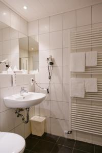 Baño blanco con lavabo y espejo en Friesen Hotel, en Jever