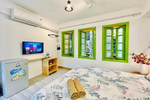 a bedroom with a bed and a tv and windows at Vitamin Home Hoàn Kiếm 35 in Hanoi