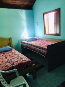 een blauwe kamer met 2 bedden en een raam bij Casa Recanto das Rosas in Monte Verde