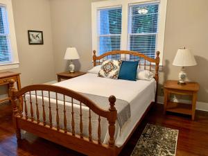 a bedroom with a wooden bed and two windows at Micanopy Countyline Cottages in Micanopy