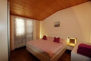 sypialnia z łóżkiem z czerwonymi poduszkami i oknem w obiekcie Apartment Drpic I w mieście Šilo