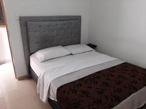 um quarto com uma cama grande e uma cabeceira cinzenta em Villa Mary Hostal em Barranquilla