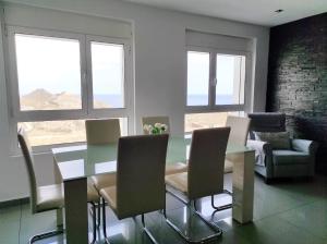 a dining room with a table and chairs and windows at Las Palmas Golf & Beach in Las Palmas de Gran Canaria