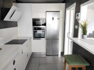 a kitchen with white cabinets and a stainless steel refrigerator at Las Palmas Golf & Beach in Las Palmas de Gran Canaria