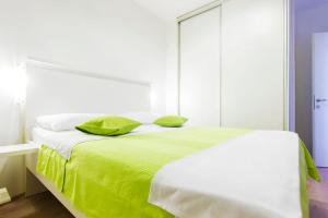 a white bed with green sheets and pillows on it at Pansion Zlatna ribica in Brodarica