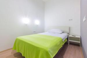 a white room with a bed with a green blanket at Pansion Zlatna ribica in Brodarica