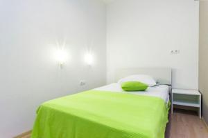 a bed with a lime green blanket on top of it at Pansion Zlatna ribica in Brodarica