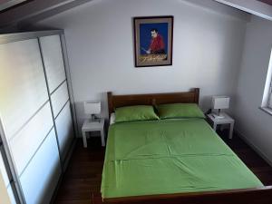 1 dormitorio con 1 cama con sábanas verdes y 2 mesas en Emonia apartman, en Novigrad Istria