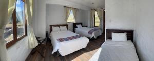 a bedroom with two beds and two windows at La Casa de Santiago Hotel in Cabanaconde