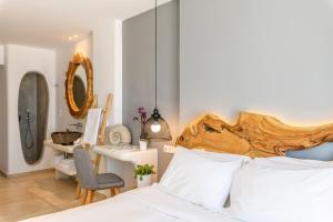 a bedroom with a bed with a wooden headboard and a desk at Casa Anna Suites in Mikonos