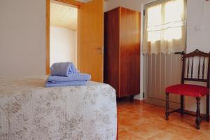 een slaapkamer met een bed, een stoel en een raam bij Casinha da Eira in Góis