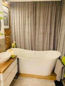 uma casa de banho com uma banheira branca e um lavatório. em Apartament MoLoo III em Ostróda