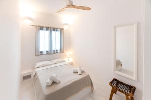 1 dormitorio blanco con 1 cama y ventilador de techo en Muses Apartments, en Ayia anna