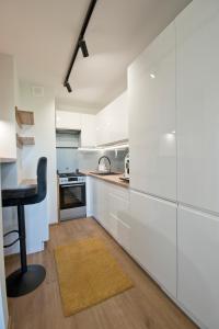 a kitchen with white cabinets and a table and a stool at Apartament Jastrzębie in Jastrzębie Zdrój