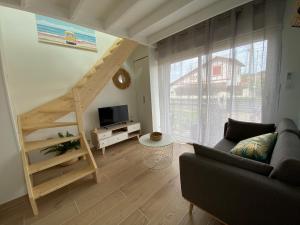 a living room with a couch and a wooden staircase at Superbe appartement climatisé avec jardin entre mer et montagne in Anglet