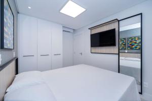 ein Schlafzimmer mit einem Bett und einem Flachbildfernseher in der Unterkunft Adra 102 - Apartamento no centro de Bombinhas - Finamente mobiliado e decorado - Rooftop com piscina e academia - À poucos metros da praia in Bombinhas + 28 Fotos