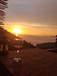 a glass of wine sitting on a table with the sunset at Grand Seaview Apartments in Ksamil