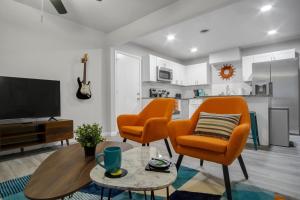 Sala de estar con 2 sillas de color naranja y TV en The Harmony Designer Home in Central DFW home en North Richland Hills