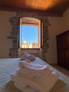 a bedroom with white towels on a bed with a window at La Vecchia Torre in Bosa