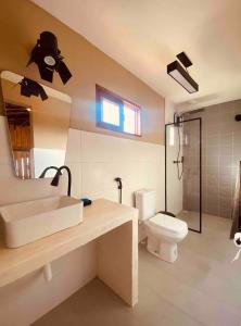a bathroom with a sink and a toilet and a mirror at Loft Canoa in Aracati
