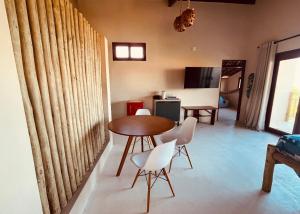 a living room with a table and white chairs at Loft Canoa in Aracati