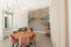 une salle à manger avec une table en bois et des chaises roses dans l'établissement Residenza Rebecca, à Trani