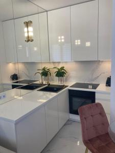 kuchnia z białymi szafkami i krzesłem w obiekcie Apartamenty Parkowe B18 w Oświęcimiu