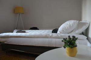 a bedroom with a bed with white sheets and a table at Apartment KAPO- Klima,Parking in Sarajevo