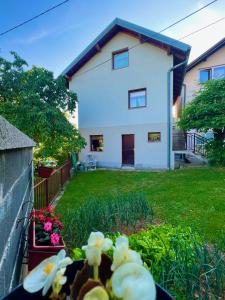 a white house with a yard with flowers at Apartman Amila in Sarajevo