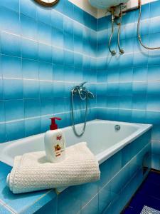 a blue tiled bathroom with a bath tub and a bottle of soap at Apartman Amila in Sarajevo