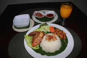a table with a plate of food and a glass of orange juice at Dangin Mangkalan Homestay in Munduk